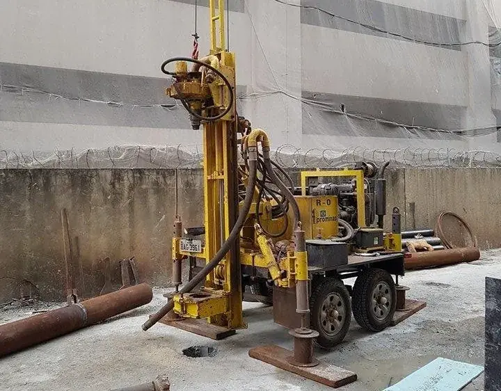 Perfuratriz R-0 posicionada em pátio de edifício, operando em área de acesso restrito